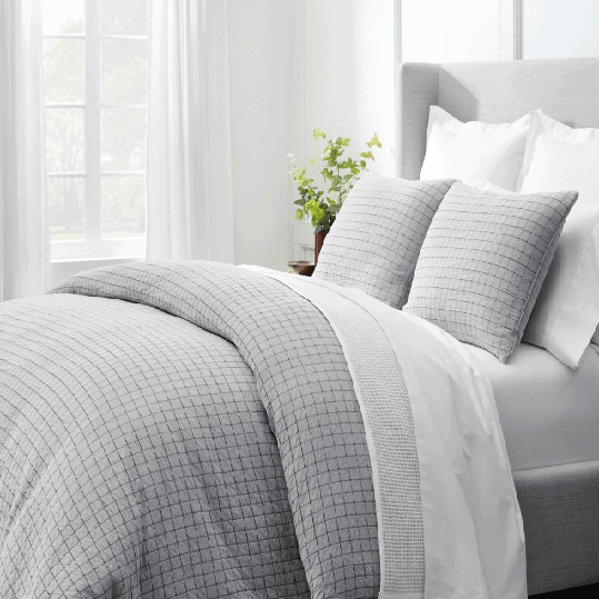 Gray and white Boll & Branch comforter and sheets on bed