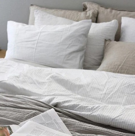 Light colored Brooklinen sheets and pillows on a bed.