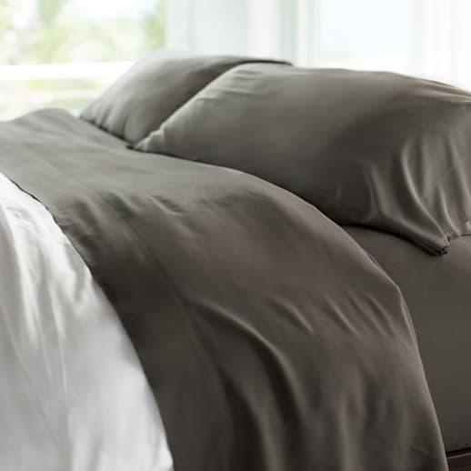 Dark gray Cariloha sheets and pillows on a bed.